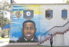 Un hombre toma el mural de Ahmaud Arbery en su teléfono celular en el costado del Centro Cultural Afroamericano de Brunswick.