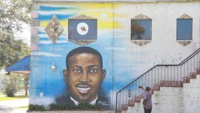 Un hombre toma el mural de Ahmaud Arbery en su teléfono celular en el costado del Centro Cultural Afroamericano de Brunswick.