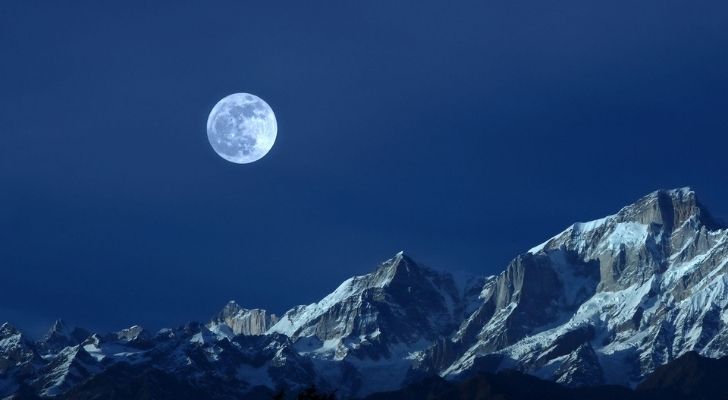 Luna fría brillante en la cima de la montaña nevada