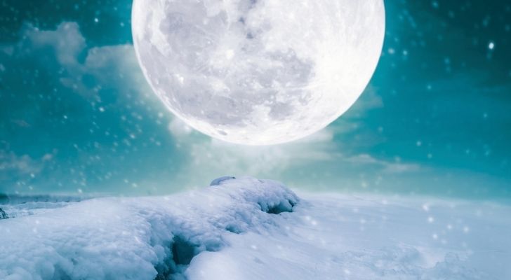 Una luna fría sobre el paisaje nevado.