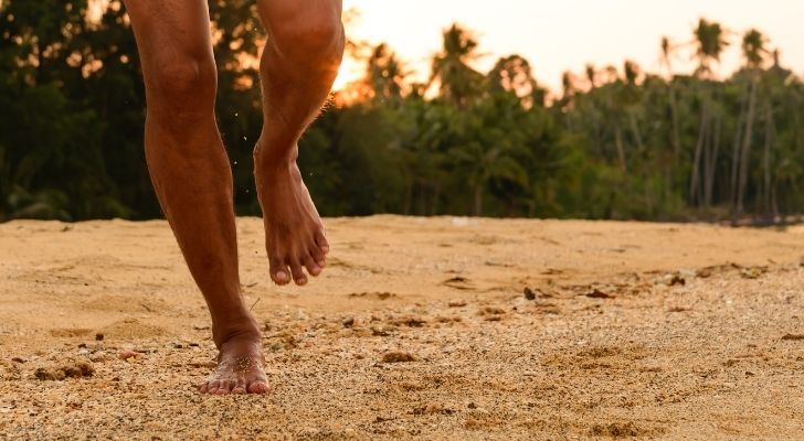 hombre corriendo descalzo en la playa