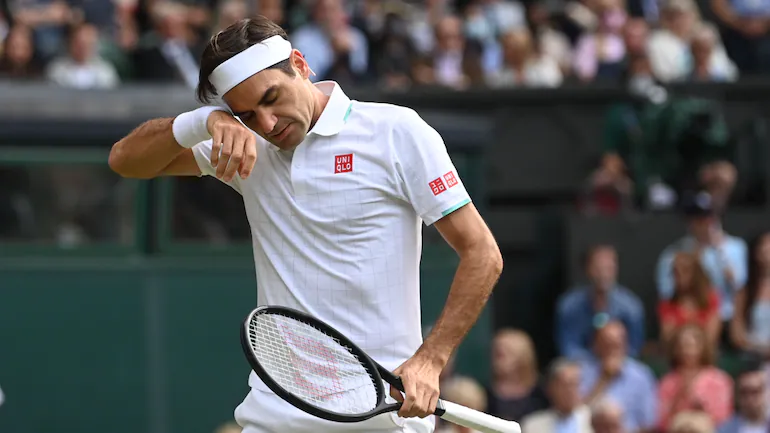 Roger Federer se limpia la frente con una banda para el sudor durante su partido de Wimbledon 2021 contra Hubert Hekatz.