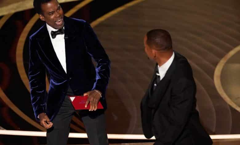 Presenter Chris Rock, left, reacts after being hit on stage by Will Smith while presenting the award for best documentary feature at the Oscars on Sunday, March 27, 2022, at the Dolby Theatre in Los Angeles. (AP Photo/Chris Pizzello)