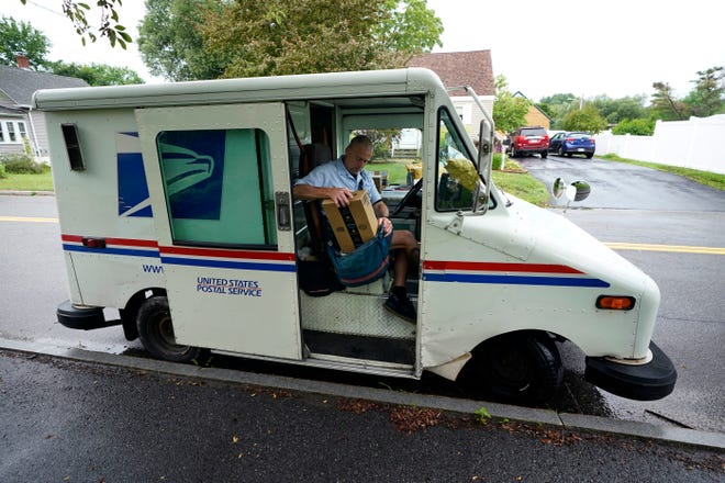 El cartero del Servicio Postal de EE. UU., John Graham, empaca el correo después de estacionar un camión de reparto de 28 años en Portland, Maine, el miércoles 14 de julio de 2021.
