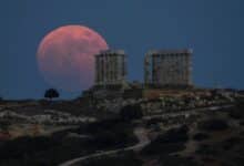 La luna llena de fresas se eleva detrás del antiguo templo de mármol de Poseidón en el cabo Sounion, a unas 45 millas al sur de Atenas, el jueves 24 de junio de 2021.