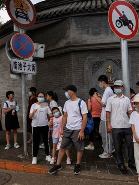 FOTO DE ARCHIVO: Las personas usan máscaras faciales mientras están de pie en una calle después de un brote de la enfermedad por coronavirus (COVID-19), en Beijing.