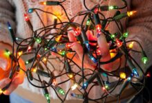 A person holds a knotted ball of Christmas lights.