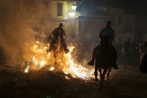 Montar a caballo a través de hogueras durante el festival anual de Luminarias en España