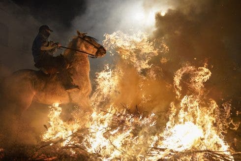 Montar a caballo a través de hogueras durante el festival anual de Luminarias en España