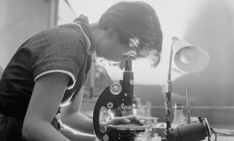 A woman looks into a microscope.