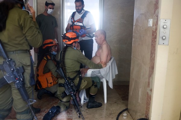 Personal médico y fuerzas de seguridad israelíes atienden a un hombre en el lugar del impacto de un cohete en la Franja de Gaza, el sábado 7 de octubre de 2023, en Ashkelon, sur de Israel. El grupo militante Hamas en Gaza disparó miles de cohetes el sábado. Amplia acción militar contra Israel.  (Foto AP/Oren Ziff)