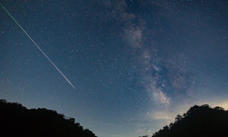 A meteor shoots across the night sky sky leaving a trail of light across the milky way