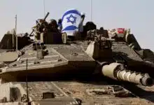 Israeli soldiers hold an Israeli flag, as they ride in a Merkava tank, near Israel's border after leaving Gaza in Israel, November 24, 2023. (Reuters, file)